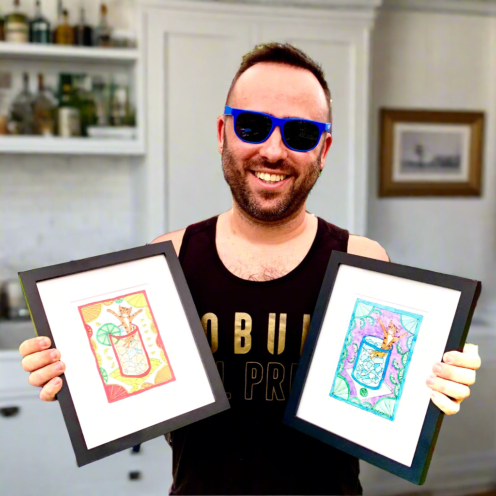 man at home holding two framed art prints of Superpussy, an orange cat