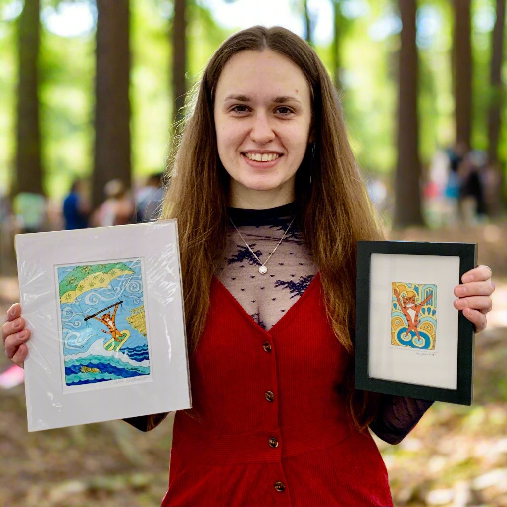 A woman holding A print featuring Superpussy-a cartoon orange cat-who is windsurfing!