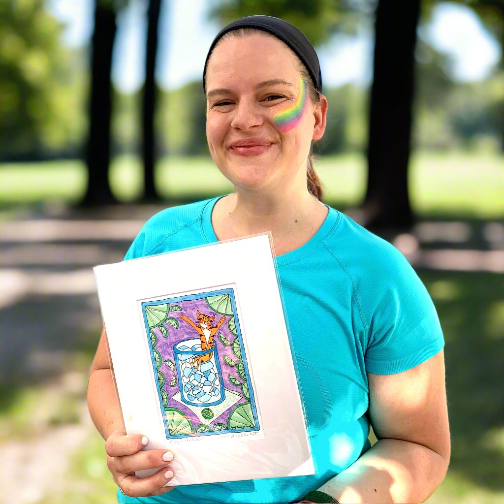 woman holding an art print of Superpussy, an orange cat sitting in a glass full of ice. Limes border the edges.