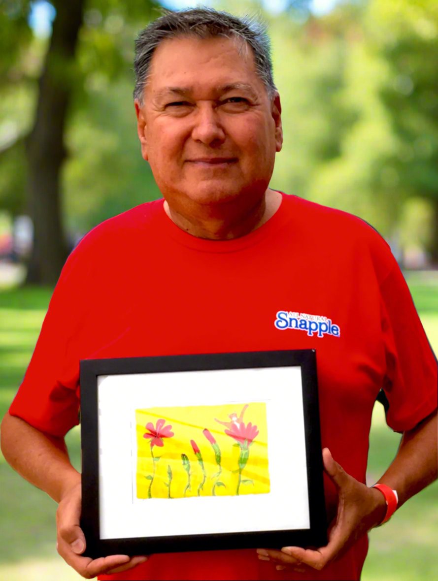 man holding framed drawing of Superpussy, an orange cat blossoming out a red flower.
